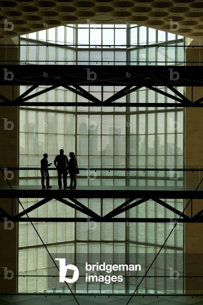 Silhouette of people in front of large window in the Museum of Islamic Art to the modern city skyline of Doha, Doha, Qatar (photo)
