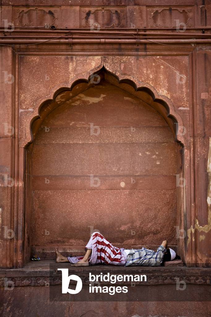 A Man sleeping under the Arch on the Side of the Jama Masjid, Delhi India (photo)