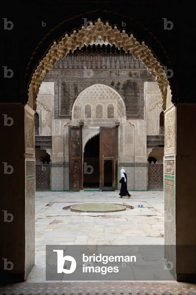Morocco, Woman walking across courtyard of Medersa Bou Inania, Fez (photo)