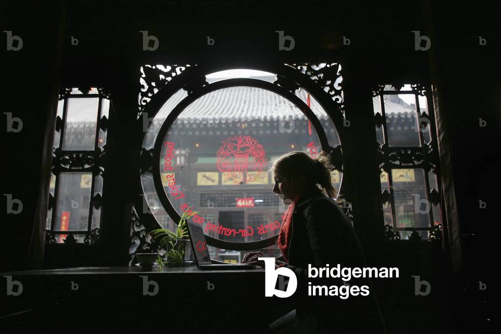 A Female Tourist Using The Internet on A Laptop in A Guesthouse in Pingyao, A Unesco World Heritage Site, Shanxi Province, China (photo)