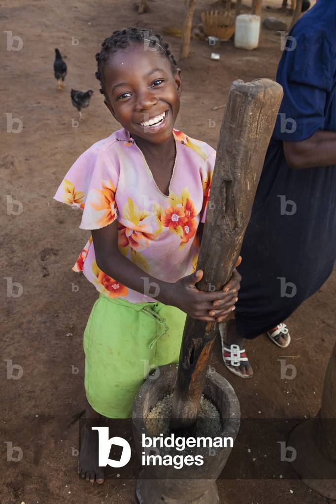 A Girl Pounding Corn Into Flour by Hand, Manica, Mozambique, Africa (photo)