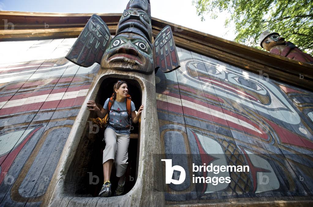 Woman Explores The Clan House At Totem Bight State Historical Park Near Ketchikan, Southeast Alaska, Summer (photo)