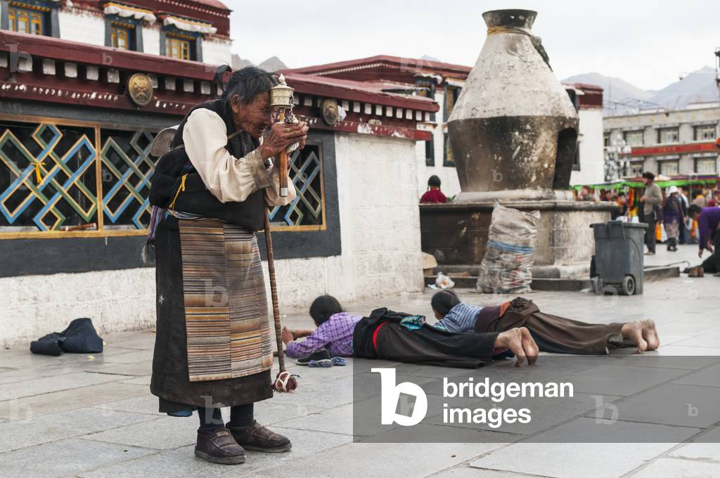 A old woman prays in front of Jokhang Temple, Lhasa, Tibet, China (photo)