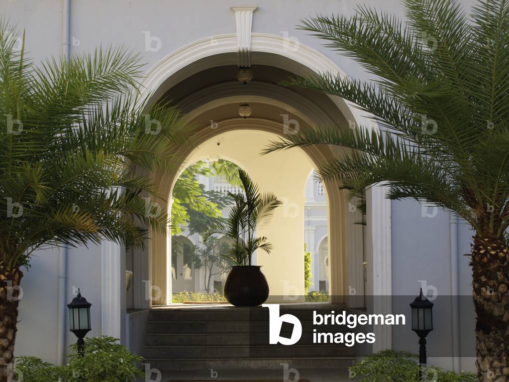 Steps leading up into an arched entryway with lamp posts and palm trees (photo)