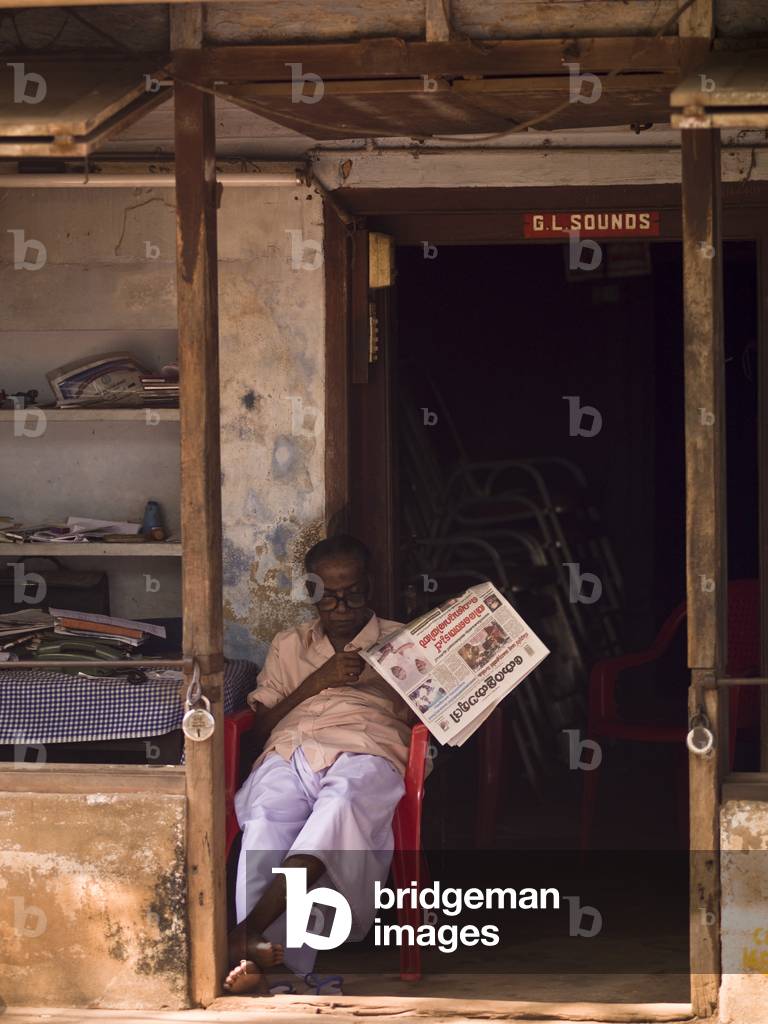 Man Reading a Newspaper in front of a Doorway, Alleppey, Kerala, India (photo)