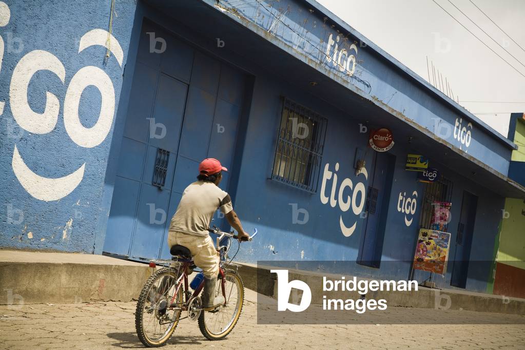 Central America, Man Cycling through a Shopping District, Patzicia, Guatemala (photo)