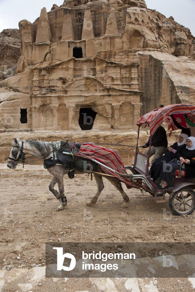 A horse pulling a carriage of tourists at the UNESCO World Heritage site of Petra, one of the new Seven Wonders of the World, Jordan (photo)