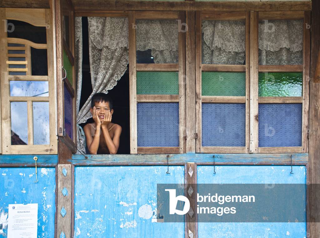A Boy looking out the Window of His House, Prabumulih Timur Sumatera Selatan Indonesia (photo)