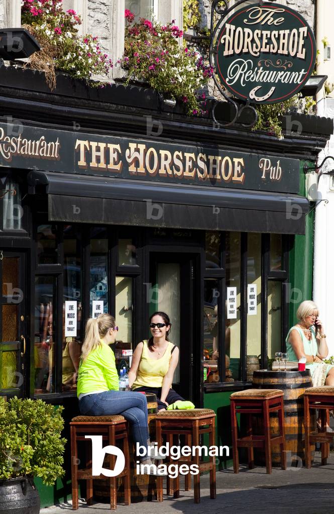 Two women talking on the outdoor restaurant patio; Kenmare, County Kerry, Ireland (photo)