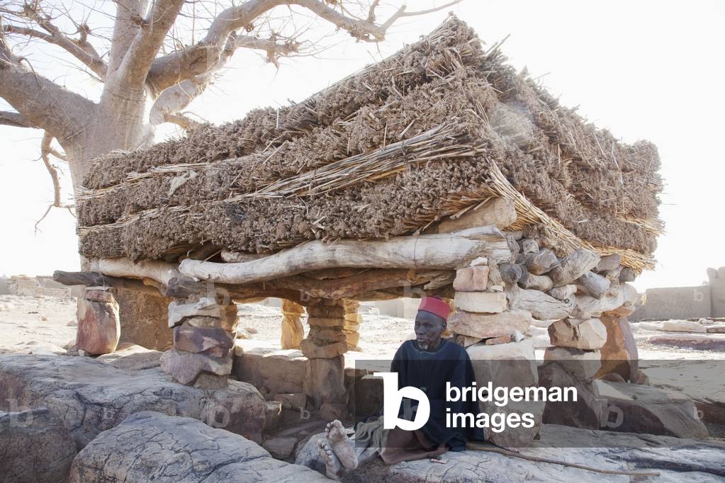 Senior man in front of the Toguna (House of Words) in Sangha, Mali (photo)