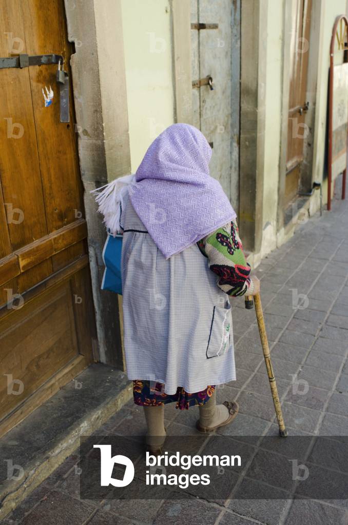 Senior woman with cane walking on sidewalk, Guanajuato, Mexico (photo)