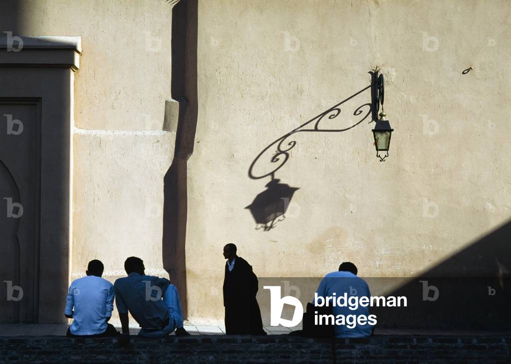 Men relaxing in Shadow of Koutoubia Mosque, Marrakesh, Morocco (photo)