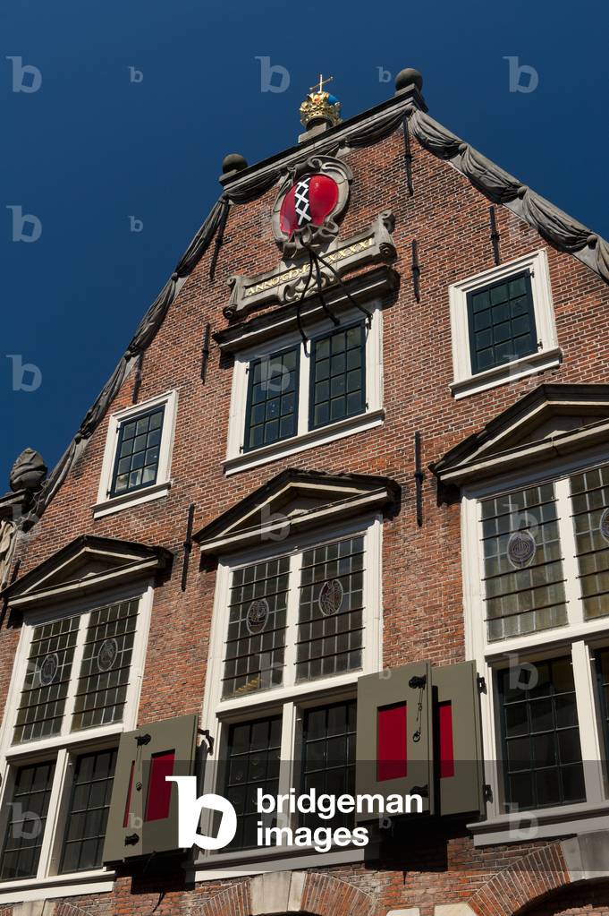 Traditional Dutch building with coat of arms of Amsterdam at top, three white crosses on black and red, Holland (photo)