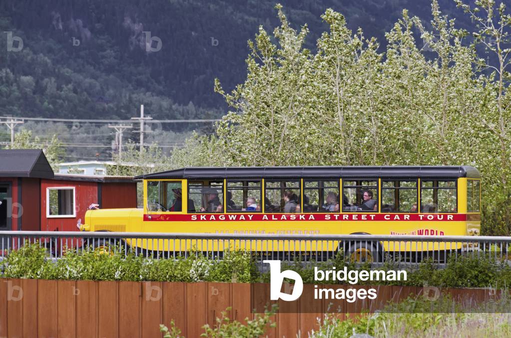 1927 sightseeing bus belonging to the Skagway Alaska Streetcar Tour travels along 2nd Avenue in downtown Skagway, Alaska (photo)