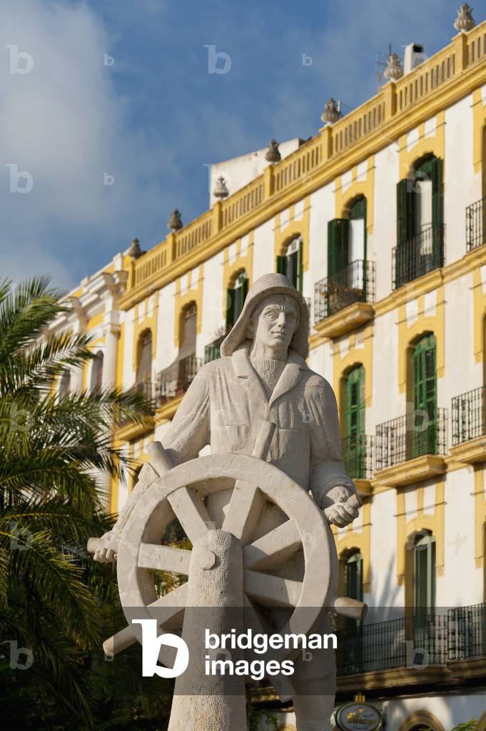 Spain, Ibiza, Statue of sailor at helm in front of old residential building, Ibiza Town (photo)