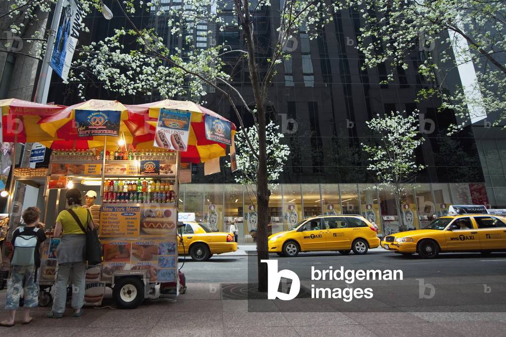 Man Selling Hot Dogs  and Taxis Passing in Front of The Museum of Modern Art Also Known As Moma, Manhattan, New York, USA (photo)