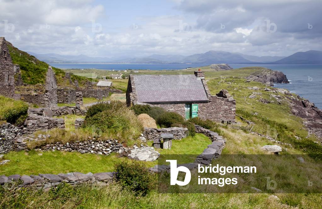 A house with green door on a grassy ridge overlooking the water with mountains in the distance, near Castlegrove; County Kerry, Ireland (photo)