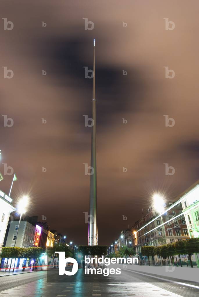 Lights illuminate buildings along a street at nighttime and the Spire of Dublin; Dublin, Ireland (photo)