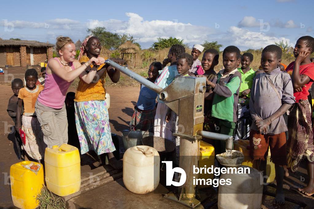 Two Young Women Pump Water At the Well As the Children Watch, Manica, Mozambique, Africa (photo)