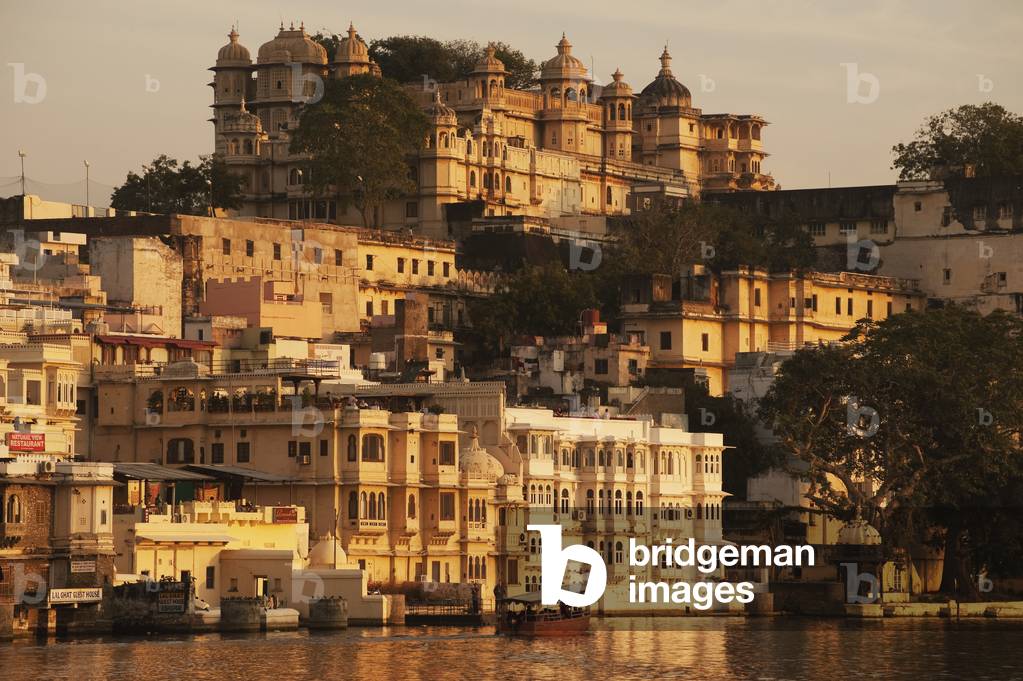 Buildings glowing in the sunlight of the setting sun along the river, Udaipur, India (photo)