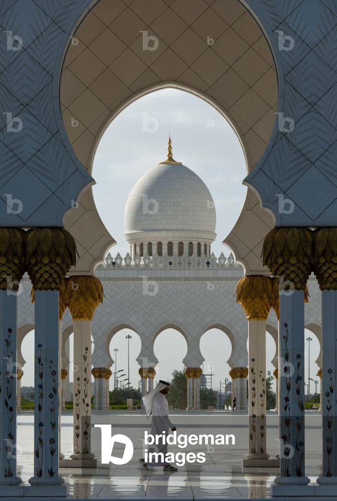 Arab Man Walking Past Courtyard of the Sheikh Zayed Grand Mosqueabu Dhabi, United Arab Emirates (photo)
