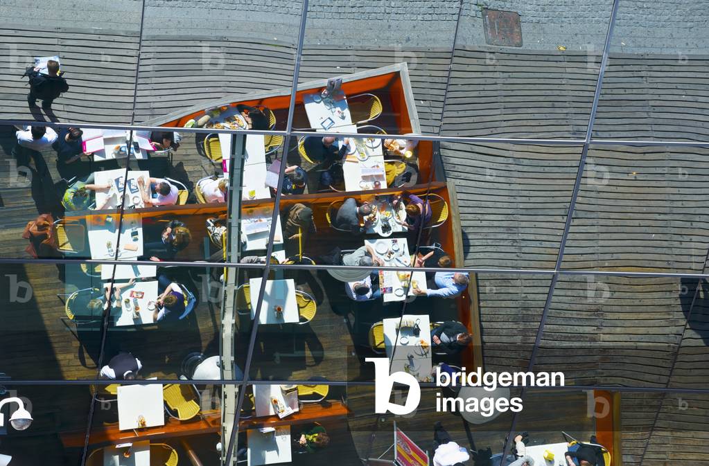 Reflection of restaurant outdoor patio seating in the mirrored wall of a building, Barcelona, Spain (photo)