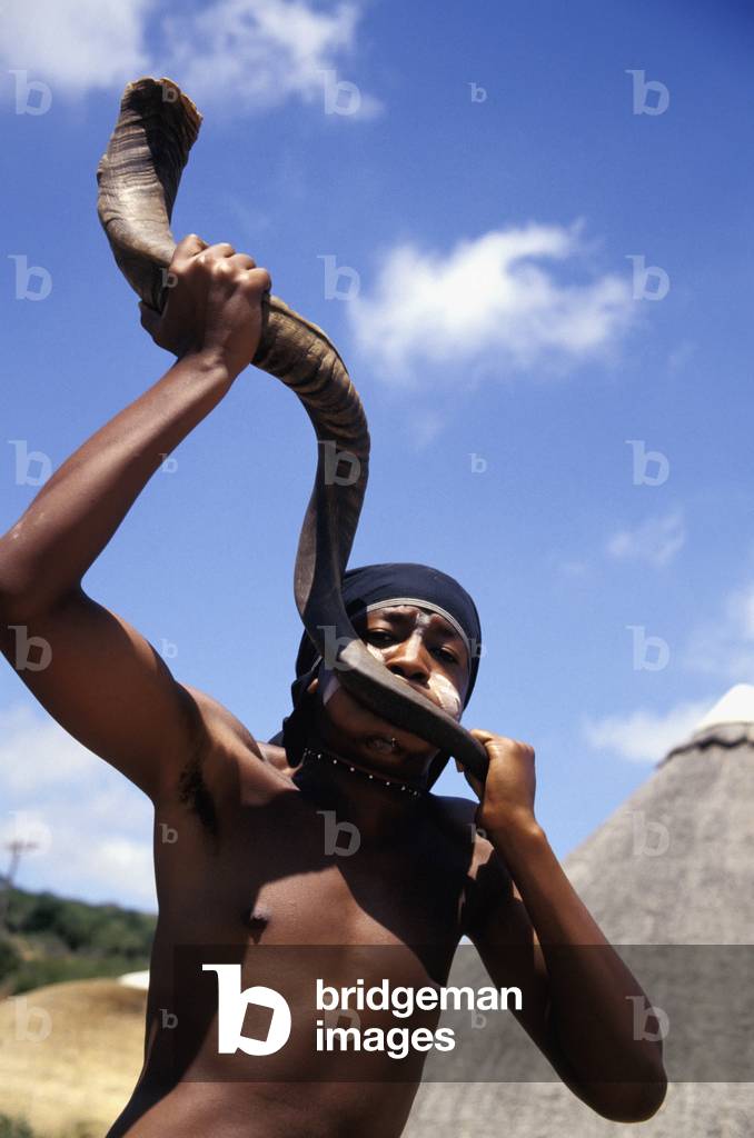 Man Blowing Into Horn Instrument, Shamwari (photo)