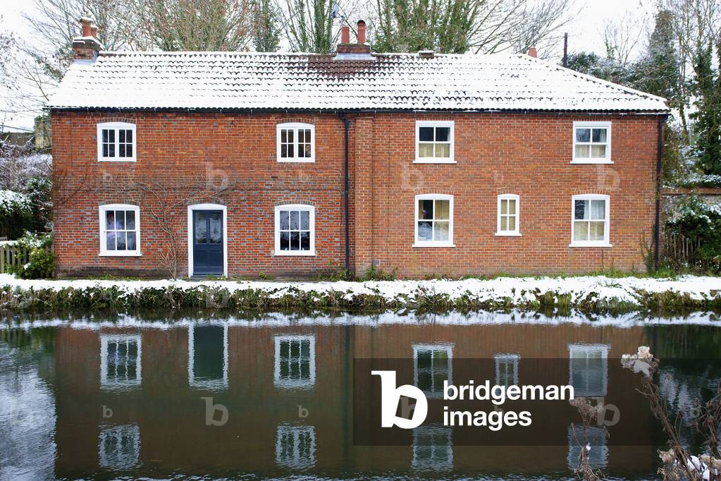 House on the edge of a canal reflected in the tranquil water, Winchester, Hampshire, England, UK  (photo)