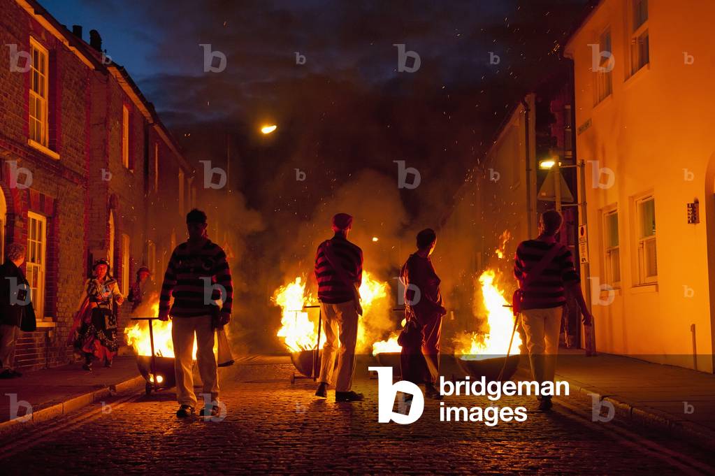 People dressed as smugglers carrying burning carts down street, Lewes, England, UK (photo)