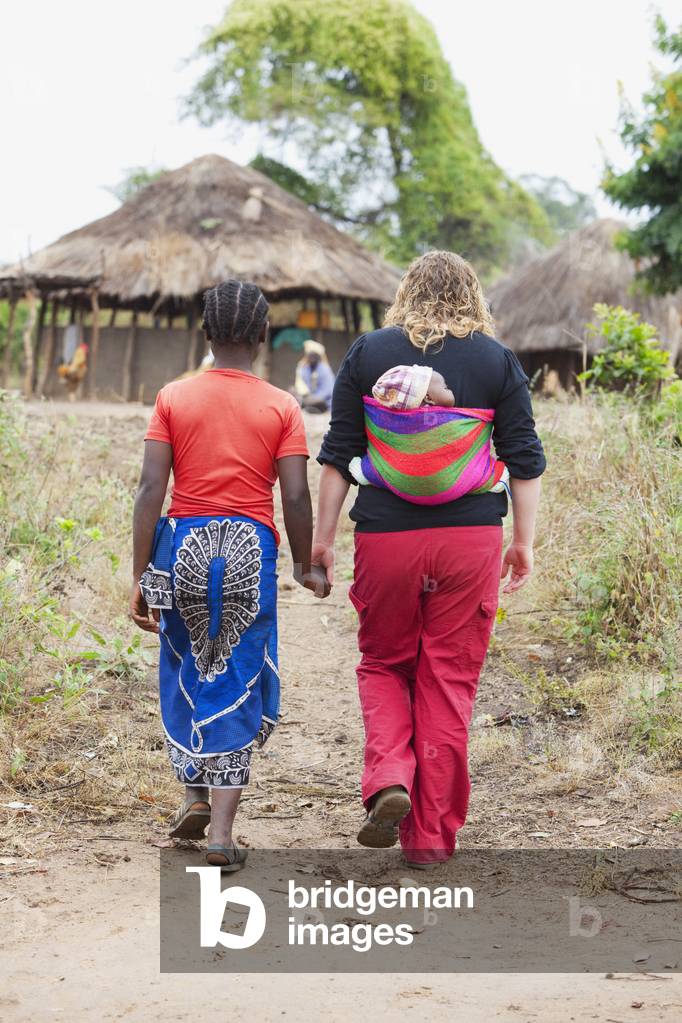 Two Women walking Together As One Carries a Baby in a Sling, Manica, Mozambique, Africa (photo)