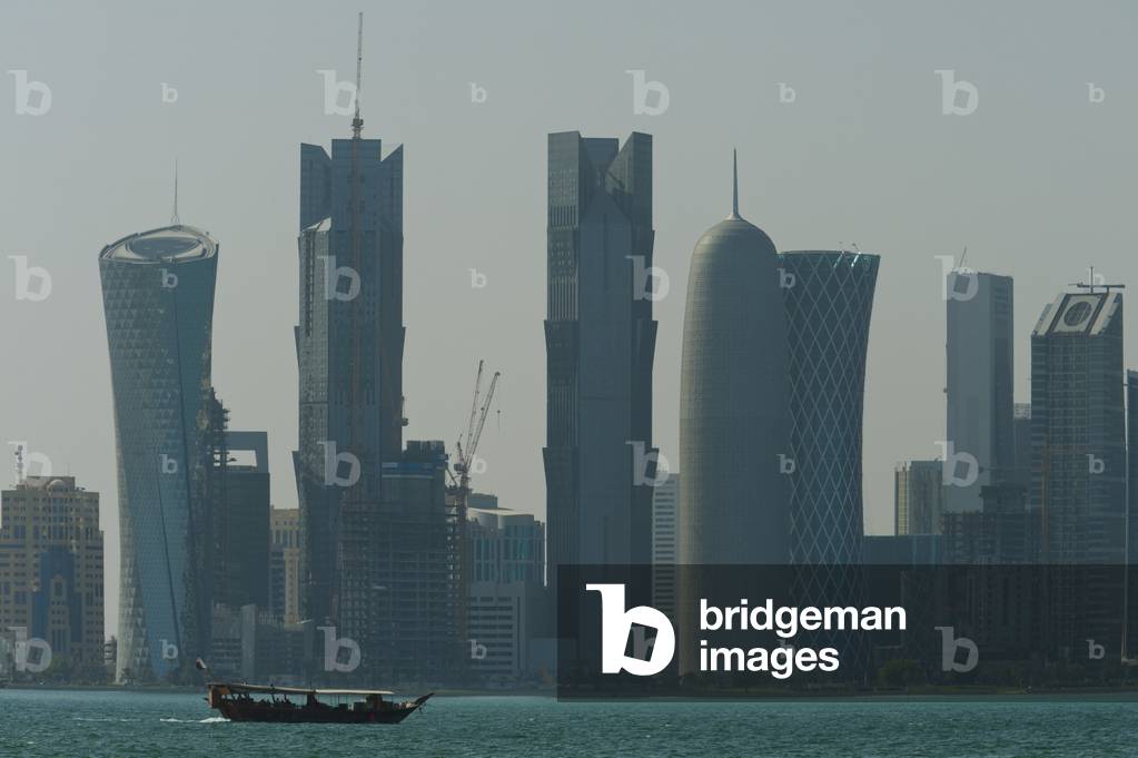 Wooden boat crossing harbour in front of the modern skyline of Doha, Doha, Qatar (photo)