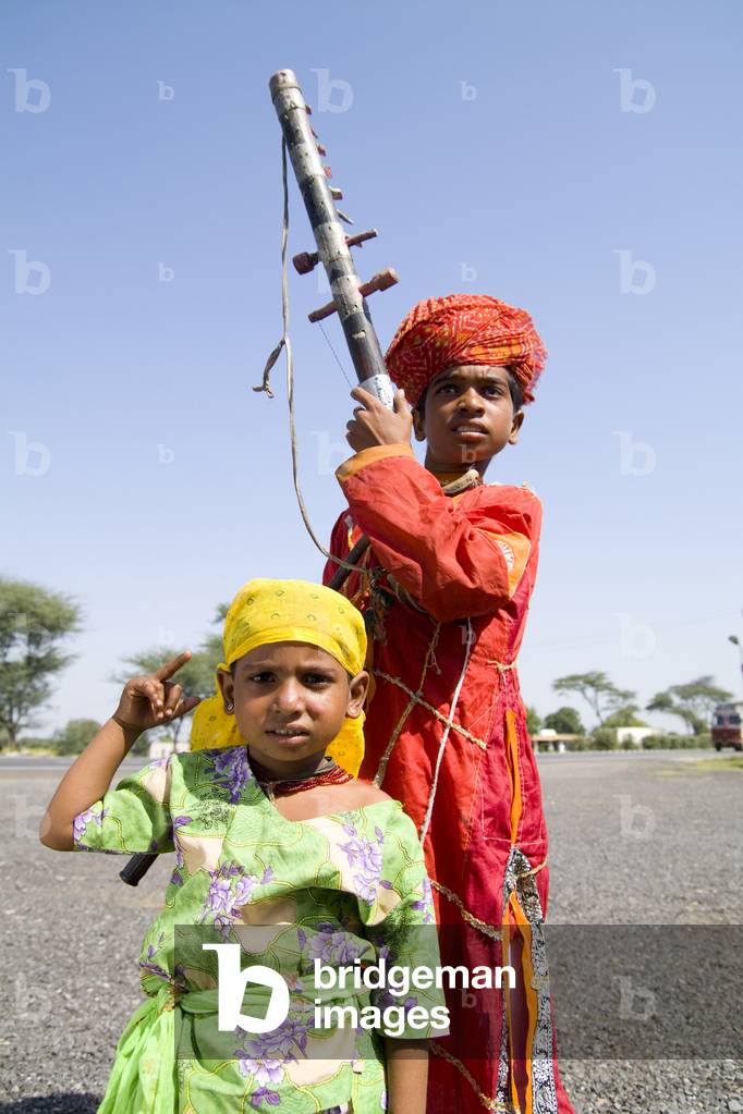 Young Boy with Musical Instrument Called Sarangi and Young Dancing Sister, Road to Jodhpur, Rajasthan, India  (photo)
