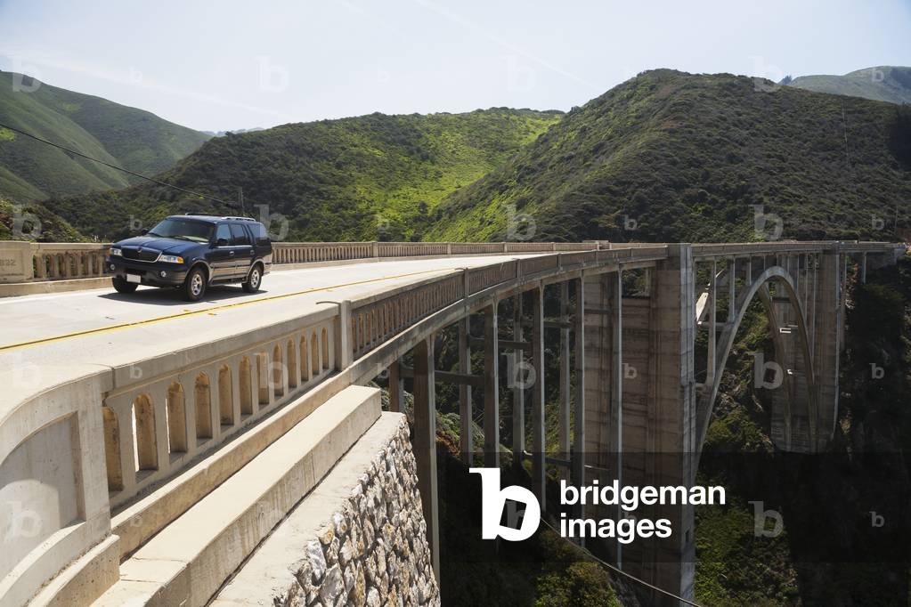 A vehicle on an elevated road going through a mountainous landscape, California, USA (photo)