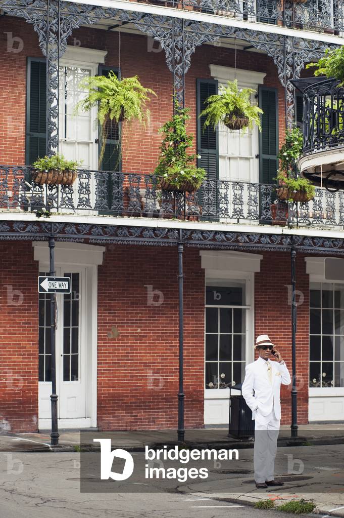 USA, Louisiana, French Quarter, New Orleans, Man in white suit standing in front of traditional housel (photo)