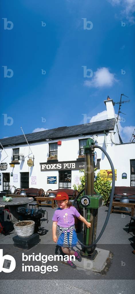 Co Wicklow, Ireland; Young Girl Standing Under Fox's Pub Sign (photo)