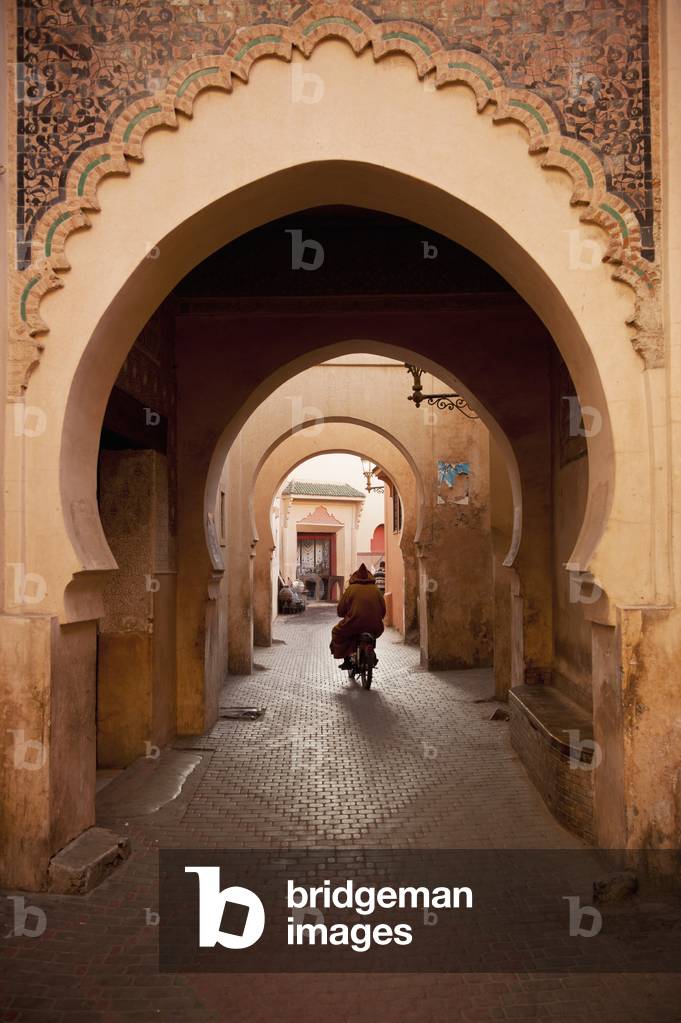 Morocco, Man on moped going through arches in alleyway in Medina of Marrakesh, Marrakesh (photo)