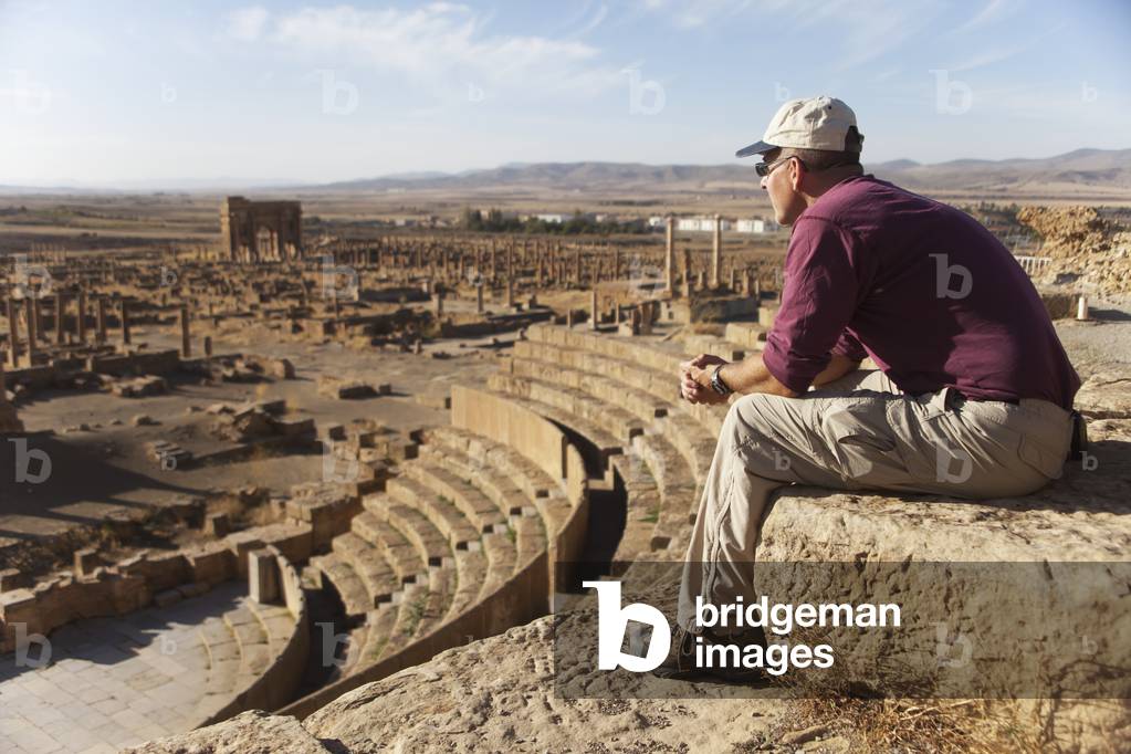 Tourist surveys the theatre and Roman ruins, Timgad, near Batna, Algeria (photo)