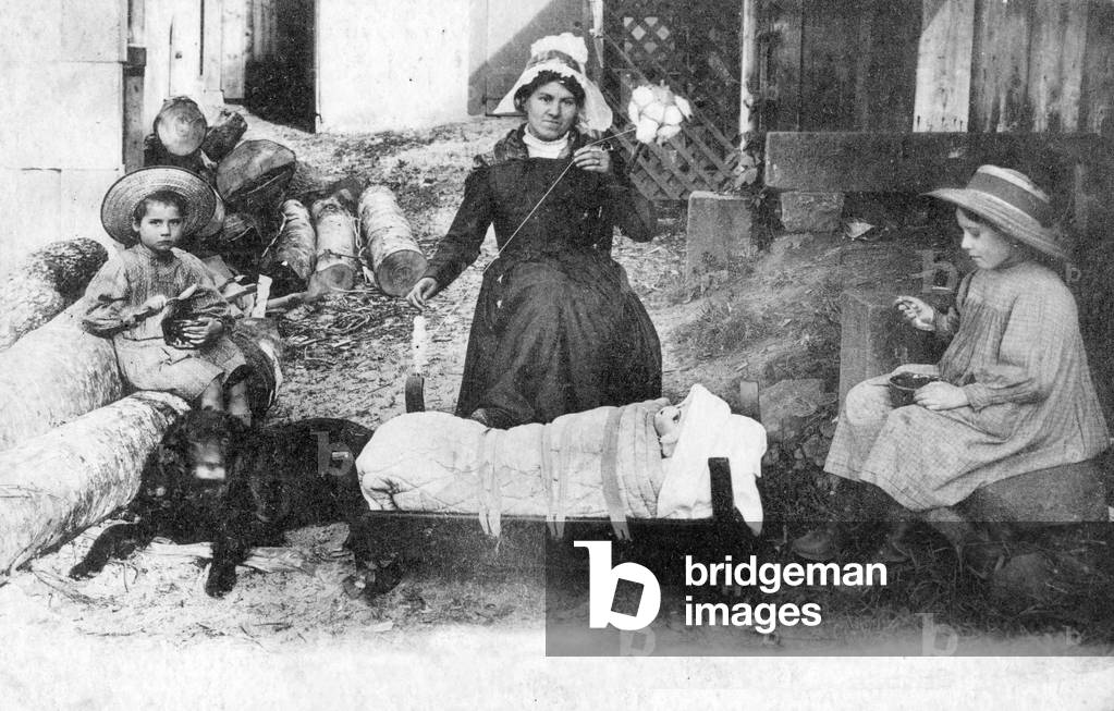 Farmers in france, the mother spins the cotton, 1900 ca postcard
