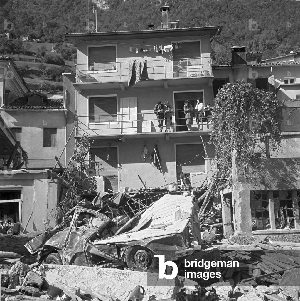 A family stands on a balcony looking at the calamity ravages, Longarone, Vajont, 9th October 1953 : Spared Family