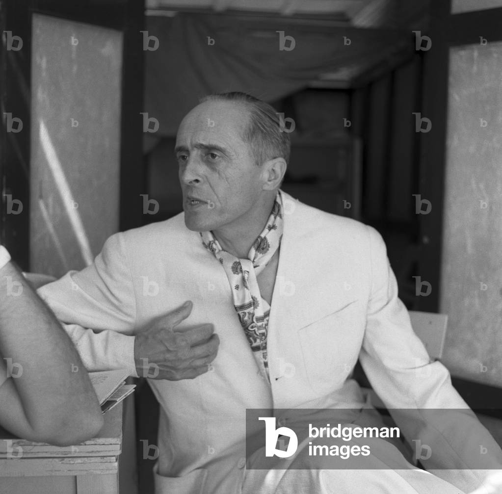 French director Rene' Clair, wearing a white suit and a foulard, portrayed in a close-up while leaning on a table, Venice, 1958