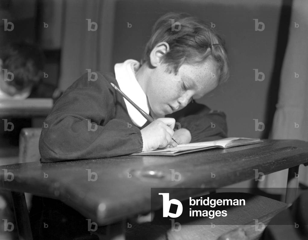 A boy writes at his desk with a cartridge pen, Venice, 1949 : Writing