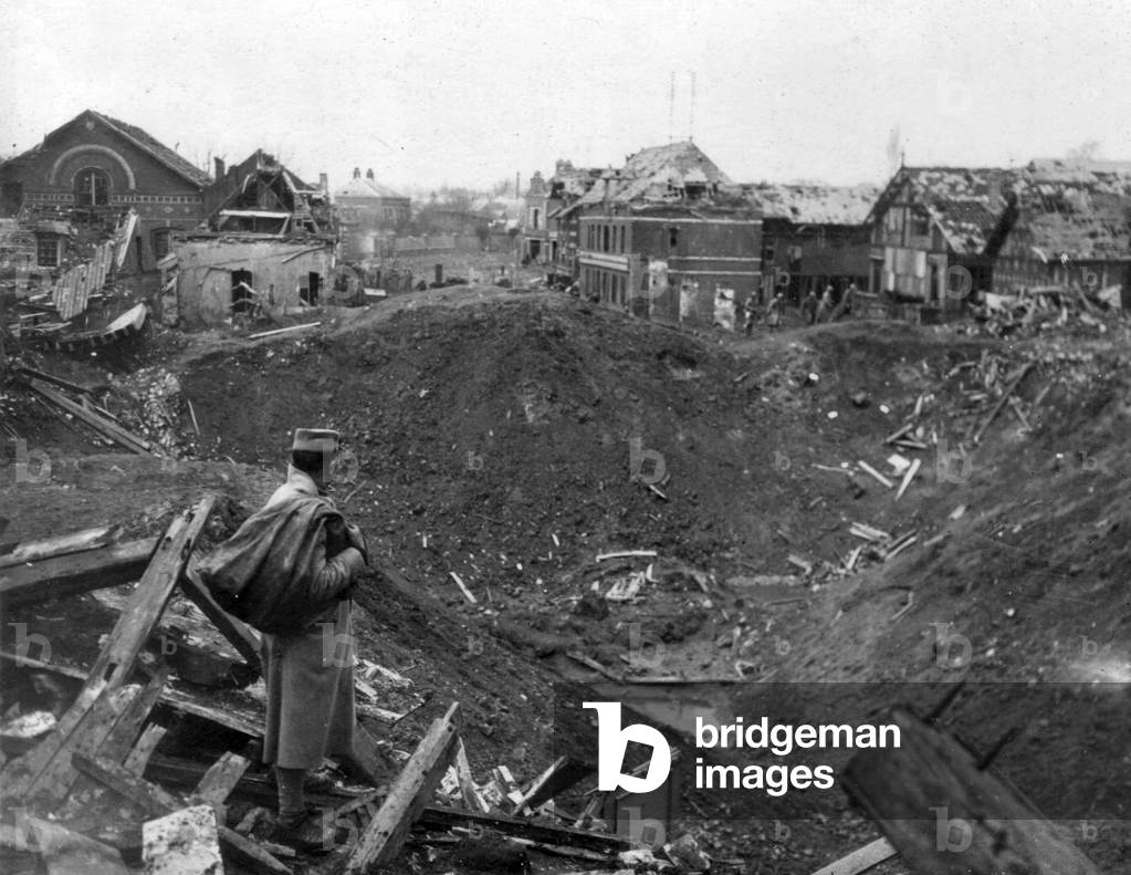 French soldier looking at a mine crater in a village, ww1 (b/w photo)