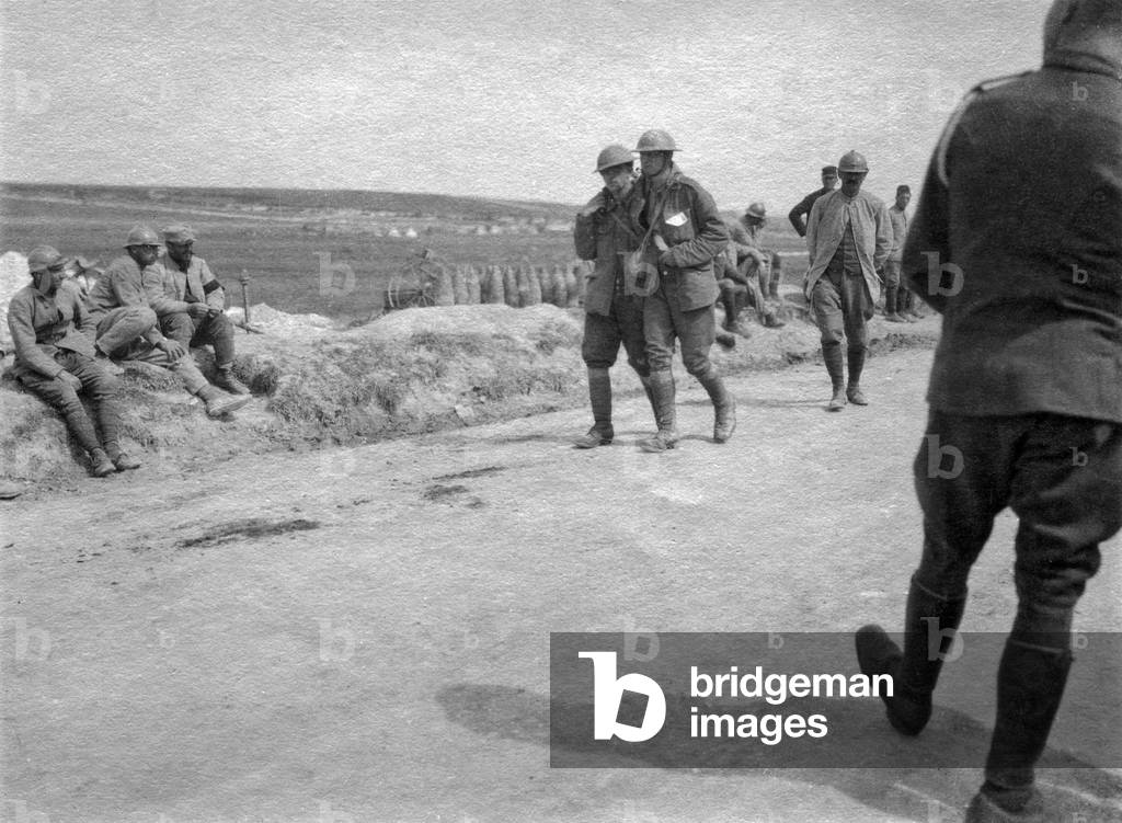 Battle of the Somme, France, July 1916 : a wounded English soldier supported by another solider under look of French soldiers (b/w photo)