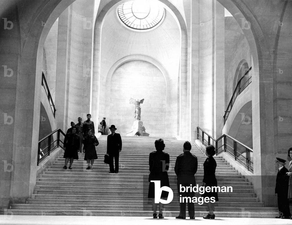 WWII:Paris (France) July 1945: A GI's and two Wacs in front of the entrance of the Louvre Museum and the staircase leading to the famous sculpture “La Victoire de Samothrace””