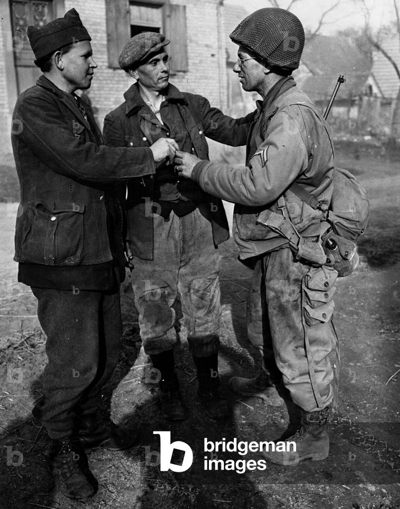 WWII:North Alsace March 18, 1945: Corporal of the 68th Infantry Batallion of a VIIe US Army armoured division offers cigarettes to sovietic force workers