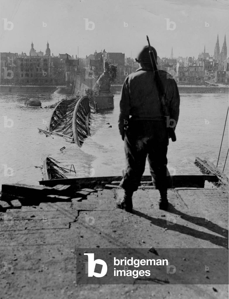 WWII:Bonn (Germany) 9 March 1945: In front of the bridge over the Rhine destroyed by German troops, a soldier of the First US Army contemplates Beuer across the river