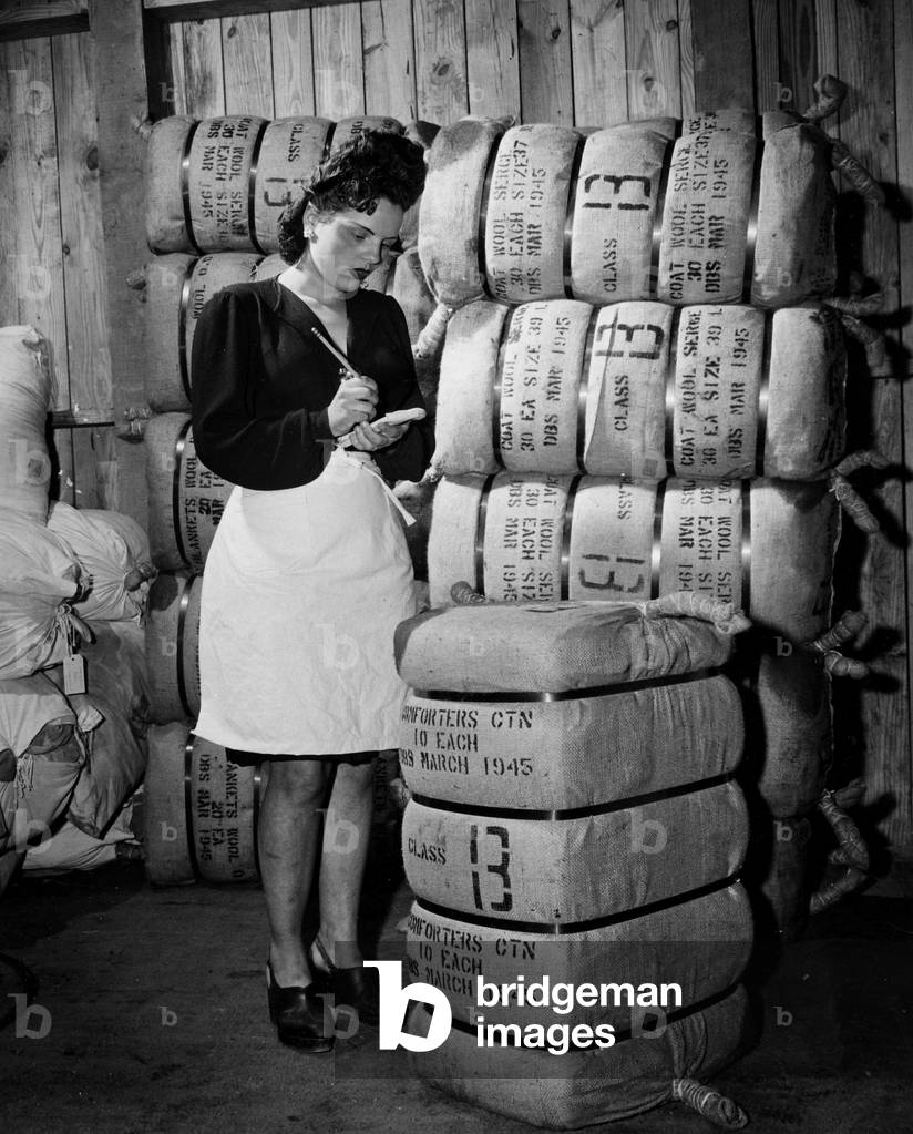 WWII:Near Marseille (Bouches du Rhone) France 3 April 1945: French employee counts the bundles of clothing for GI's at the 70th Quarter-Master Base Depot