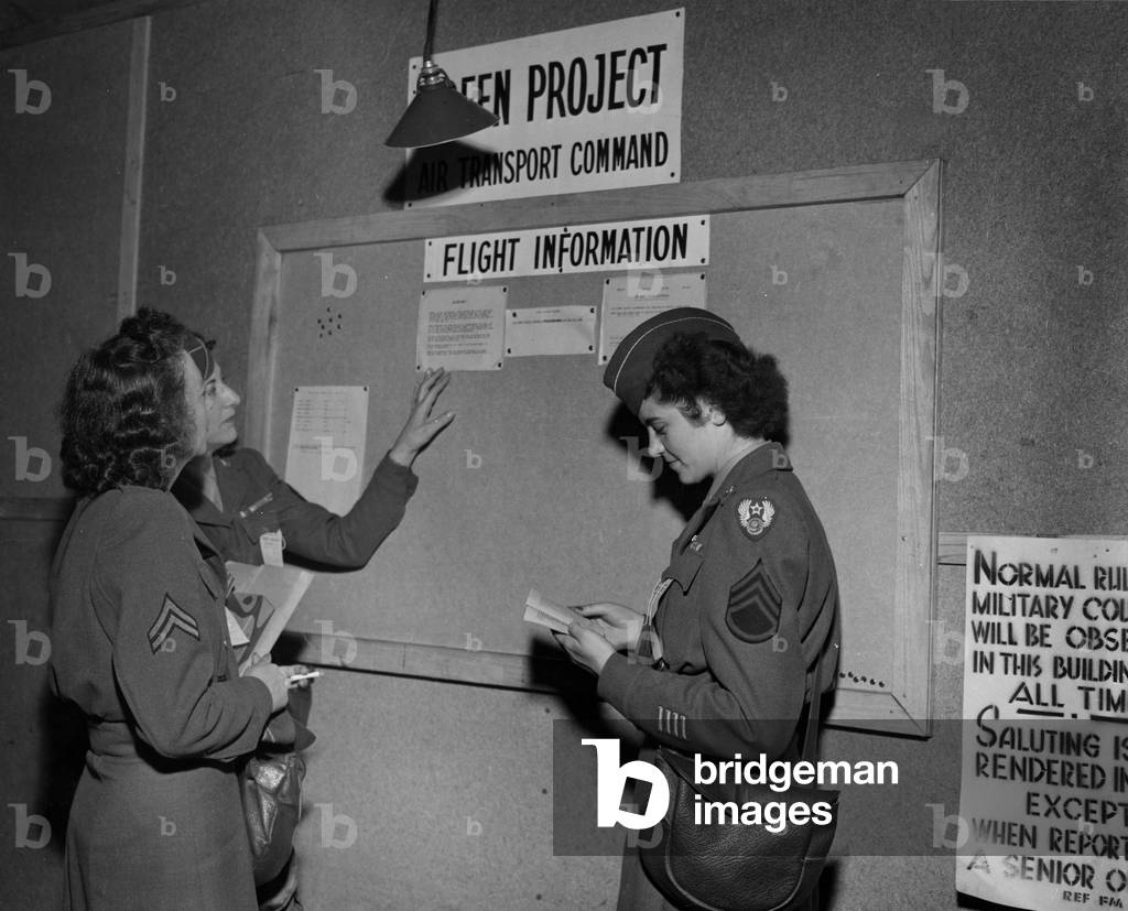WWII:Paris (France) July 14, 1945: At the Air Transport Command Information Point, these three American Wacs look at the schedule of flights that have to repatriate them to the United States because they have the number of points necessary to return home.