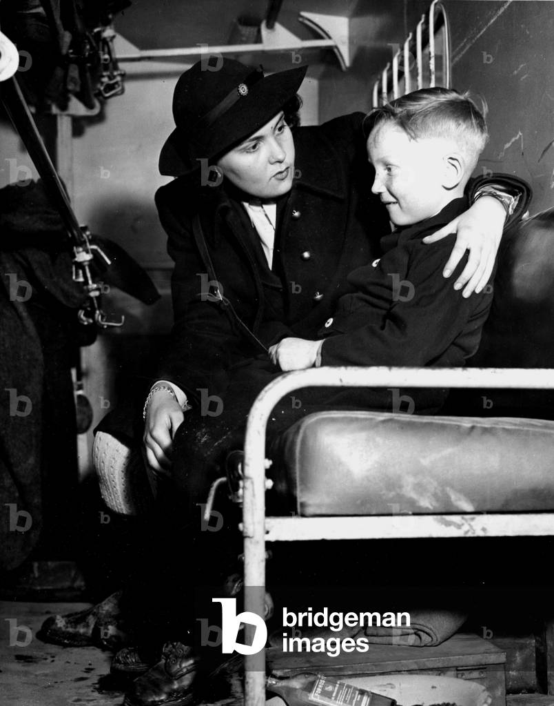 WWII:Herbitzheim (France) 17 February 1945: A French auxiliary to the 44th DI US reassists a child while an ambulance takes him to a field hospital