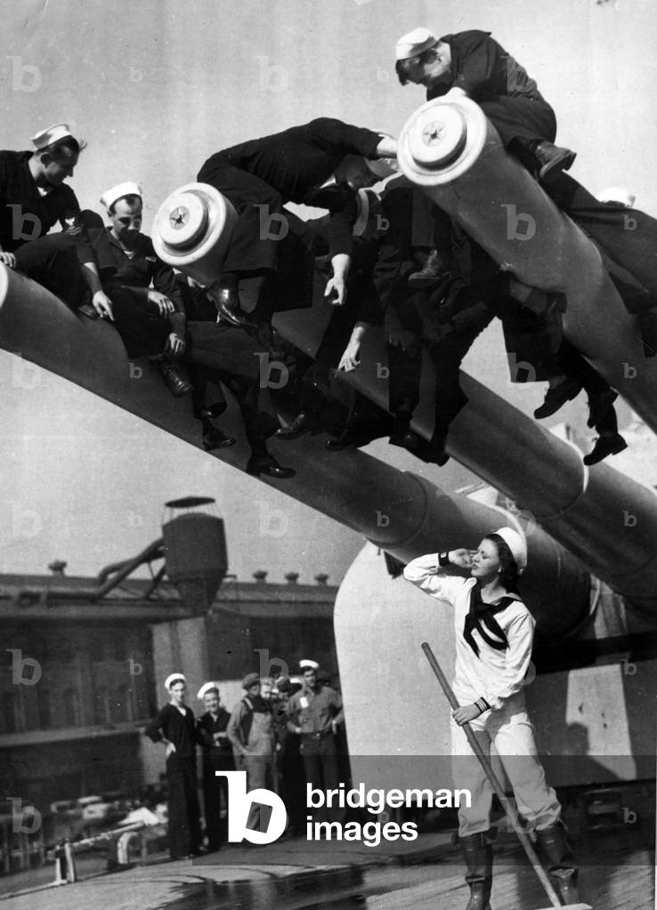 Brooklyn (NY), USA, 1930s: Actress Ginger Rodgers (1911-1995) deguised as a sailor under a battery of heavy cruiser USS Chicago (CA 29) during Navy Day October 27 - Brooklyn, NY, USA, 1930s: Ginger Rodgers scrubbing the deck of the USS Chicago (CA 29), 27th October